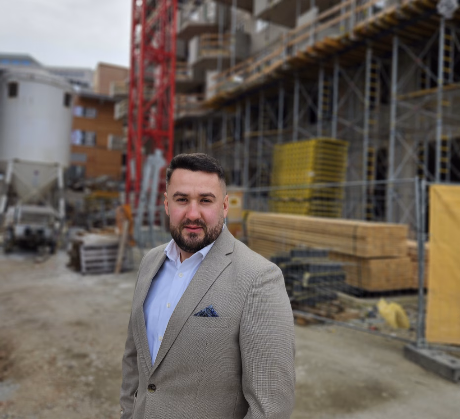 Unternehmensinhaber steht mit verschränkten Armen vor einer Baustelle.